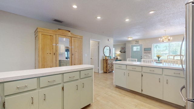 kitchen with light countertops, freestanding refrigerator, recessed lighting, a chandelier, and a textured ceiling