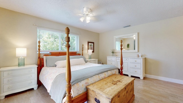 bedroom featuring a textured ceiling, light wood finished floors, baseboards, and ceiling fan
