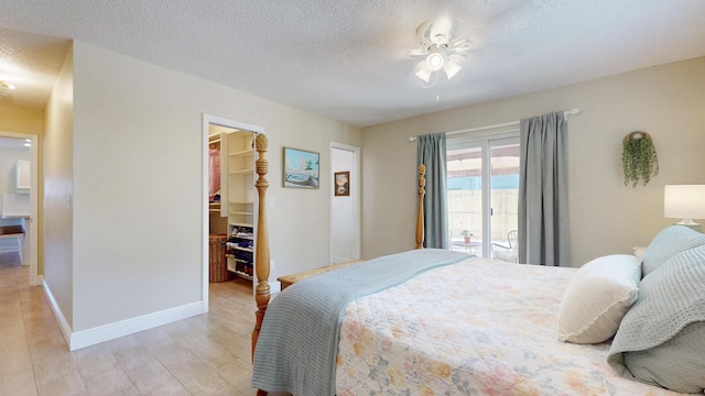 bedroom featuring a spacious closet, a textured ceiling, light wood finished floors, baseboards, and a closet