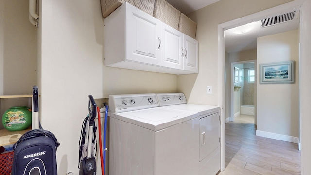 laundry room with washer and clothes dryer, cabinet space, light wood-type flooring, and baseboards