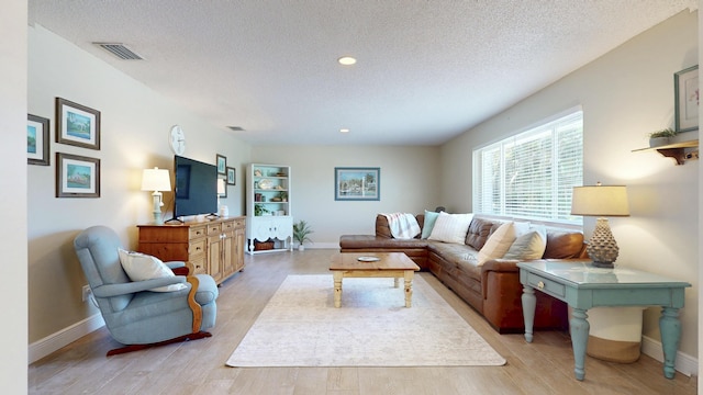 living area featuring baseboards, light wood finished floors, a textured ceiling, and recessed lighting