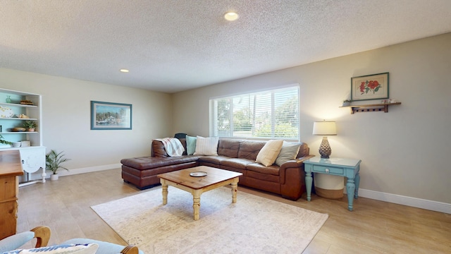 living room with a textured ceiling, light wood-type flooring, baseboards, and recessed lighting