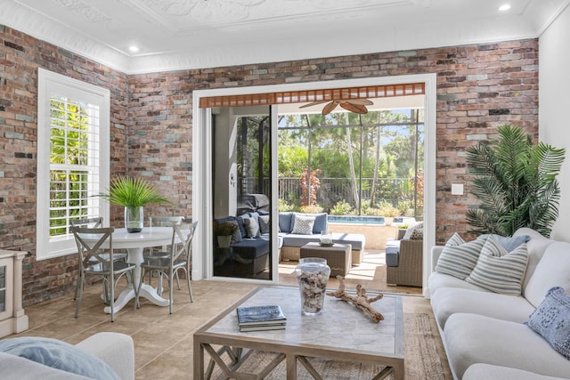 1909 Flower Dr, Palm Beach Gardens, FL 33410 - living area with plenty of natural light, light tile patterned flooring, brick wall, ornamental molding, and a ceiling fan
