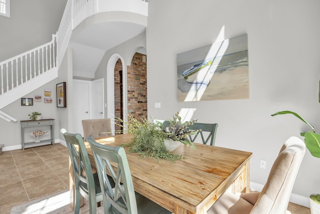1909 Flower Dr, Palm Beach Gardens, FL 33410 - dining space with arched walkways, stairway, light tile patterned floors, and a high ceiling