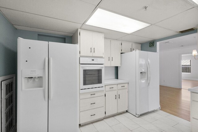 8888 SE Colony St, Hobe Sound, FL 33455 - kitchen with white appliances, a paneled ceiling, light countertops, and white cabinets