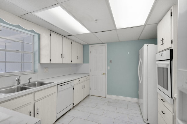 8888 SE Colony St, Hobe Sound, FL 33455 - kitchen featuring white appliances, a sink, a paneled ceiling, light countertops, and baseboards