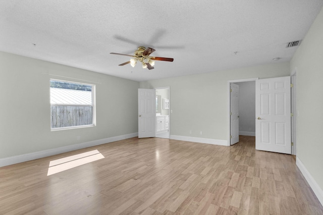 8888 SE Colony St, Hobe Sound, FL 33455 - unfurnished bedroom with light wood-type flooring, baseboards, a spacious closet, ceiling fan, and a textured ceiling