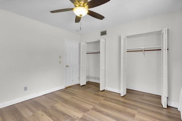 8888 SE Colony St, Hobe Sound, FL 33455 - unfurnished bedroom featuring two closets, wood finished floors, baseboards, and a ceiling fan