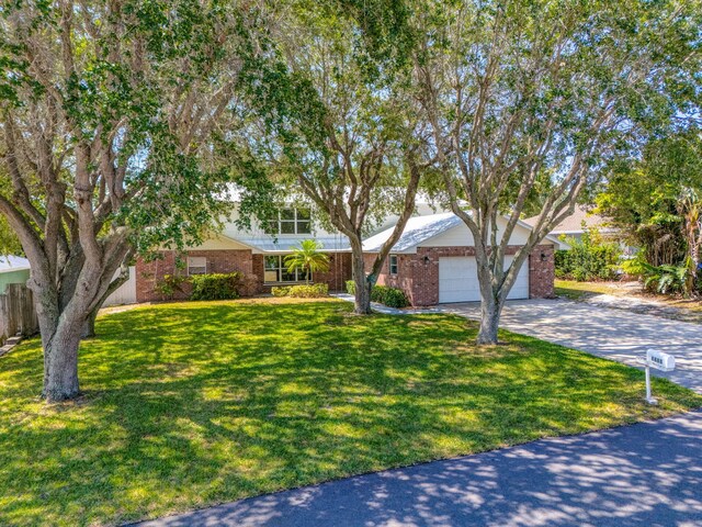 8888 SE Colony St, Hobe Sound, FL 33455 - view of front of house with an attached garage, driveway, and brick siding