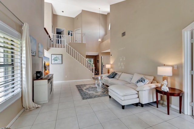 living room featuring light tile patterned flooring, stairs, baseboards, and a towering ceiling