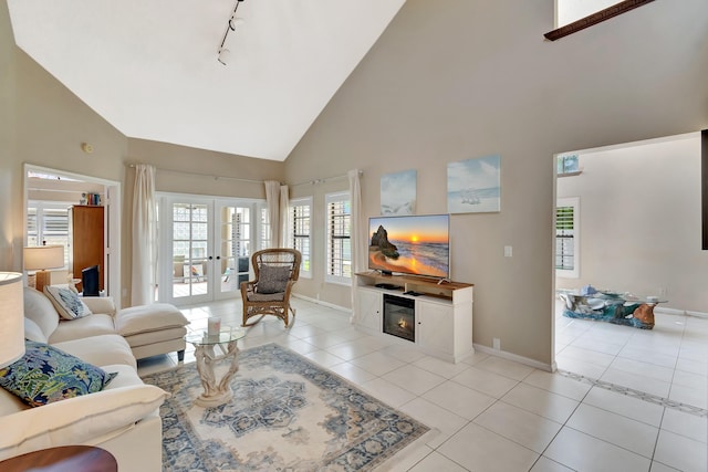 living area featuring high vaulted ceiling, light tile patterned floors, french doors, and baseboards