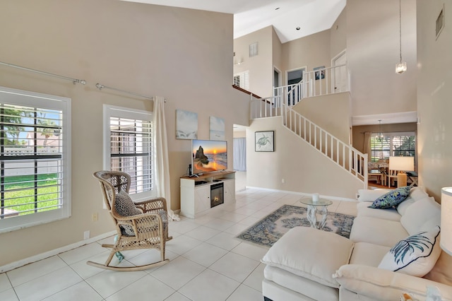 living area with stairway, a high ceiling, baseboards, and light tile patterned floors