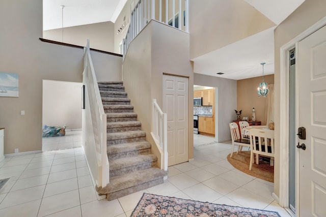 foyer featuring a high ceiling, light tile patterned flooring, and stairs