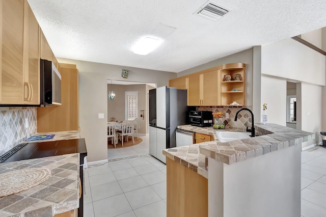 kitchen with a sink, a peninsula, light tile patterned floors, open shelves, and tasteful backsplash