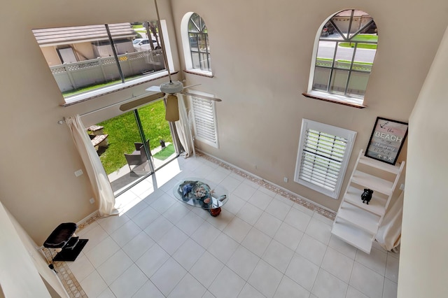 tiled foyer entrance featuring a high ceiling, healthy amount of natural light, a ceiling fan, and baseboards