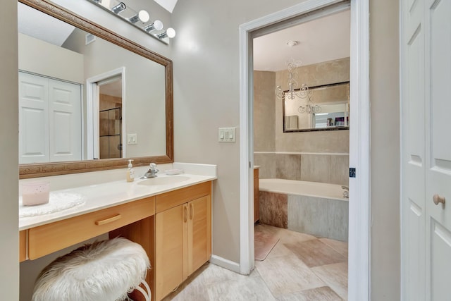 bathroom featuring tiled tub, vanity, a chandelier, tile patterned flooring, and a closet