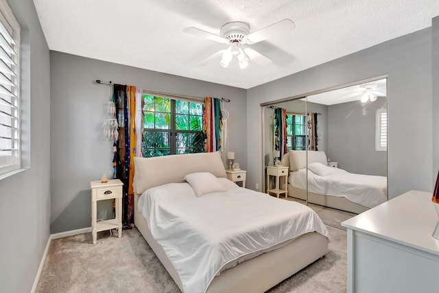 bedroom with multiple windows, a closet, light carpet, and baseboards