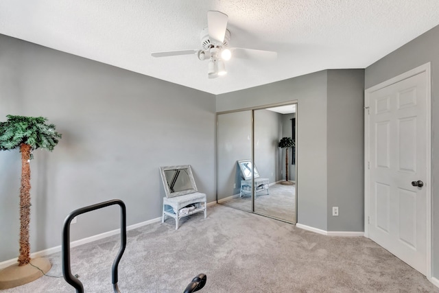 unfurnished bedroom featuring a textured ceiling, carpet, a closet, a ceiling fan, and baseboards