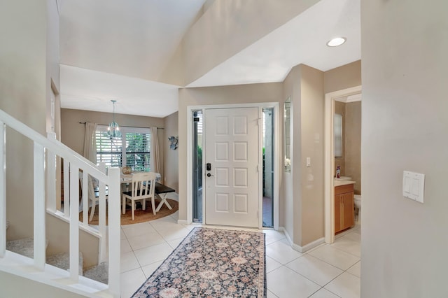 foyer entrance with light tile patterned floors, stairway, a chandelier, and baseboards