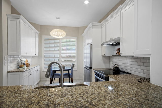 kitchen with a sink, freestanding refrigerator, under cabinet range hood, range with electric cooktop, and backsplash