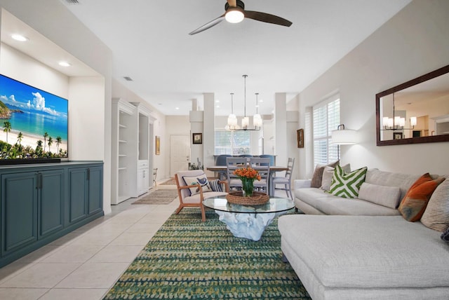 living room with a chandelier, light tile patterned floors, and ceiling fan