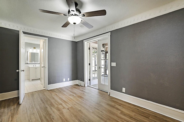 empty room featuring a ceiling fan, wood finished floors, baseboards, and a textured ceiling