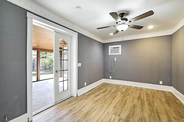 unfurnished room featuring wood finished floors, a wall unit AC, baseboards, a ceiling fan, and a smoke detector
