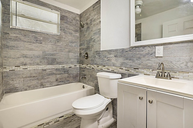 full bath with toilet, shower / tub combination, tile walls, and vanity