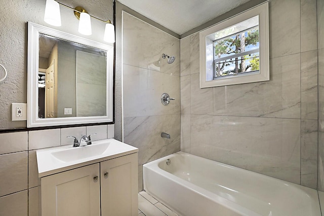 full bath with shower / tub combination, vanity, and tile walls