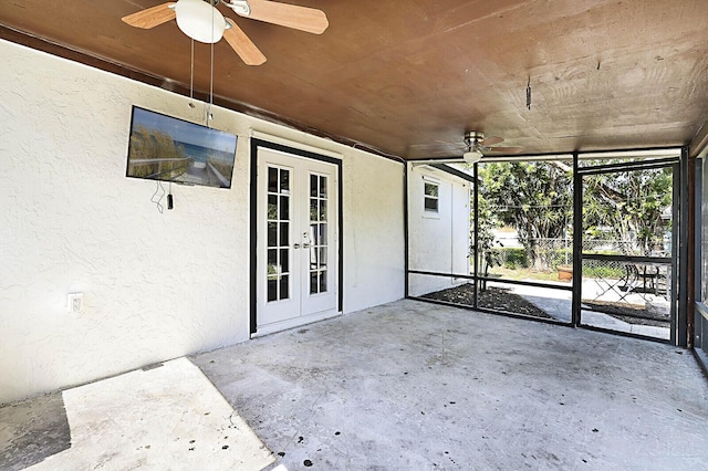 unfurnished sunroom featuring a ceiling fan and french doors