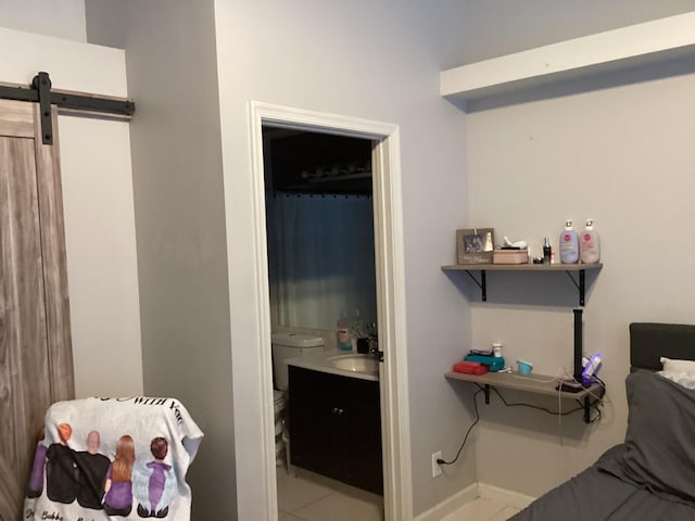 3834 SE 12th Dr, Okeechobee, FL 34974 - bedroom with baseboards, a barn door, a sink, connected bathroom, and tile patterned flooring
