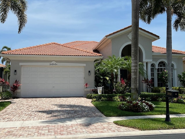 mediterranean / spanish house featuring stucco siding, a tiled roof, and decorative driveway