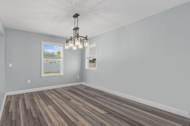 412 SW Dailey Ave, Port Saint Lucie, FL 34953 - spare room featuring a chandelier, dark wood-type flooring, and baseboards