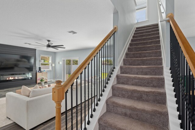 412 SW Dailey Ave, Port Saint Lucie, FL 34953 - stairway with baseboards, a glass covered fireplace, ceiling fan, and plenty of natural light