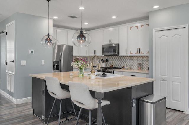 412 SW Dailey Ave, Port Saint Lucie, FL 34953 - kitchen with stainless steel appliances, wood finished floors, baseboards, decorative backsplash, and a kitchen island with sink