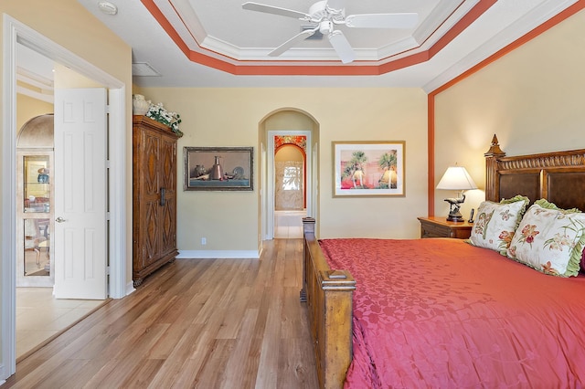 7731 Blue Heron Way, West Palm Beach, FL 33412 - bedroom with crown molding, a raised ceiling, light wood finished floors, arched walkways, and baseboards