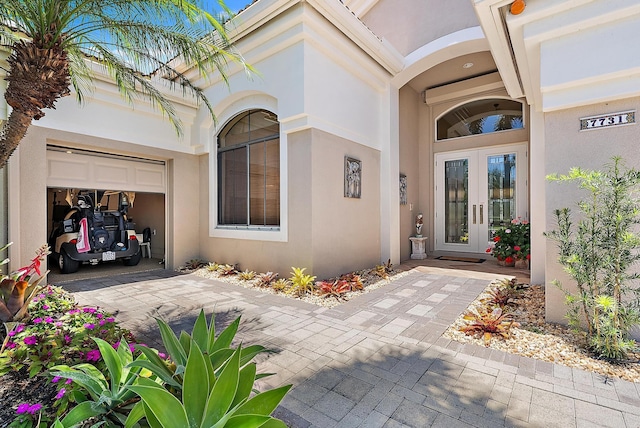 7731 Blue Heron Way, West Palm Beach, FL 33412 - property entrance featuring french doors, stucco siding, a garage, and driveway