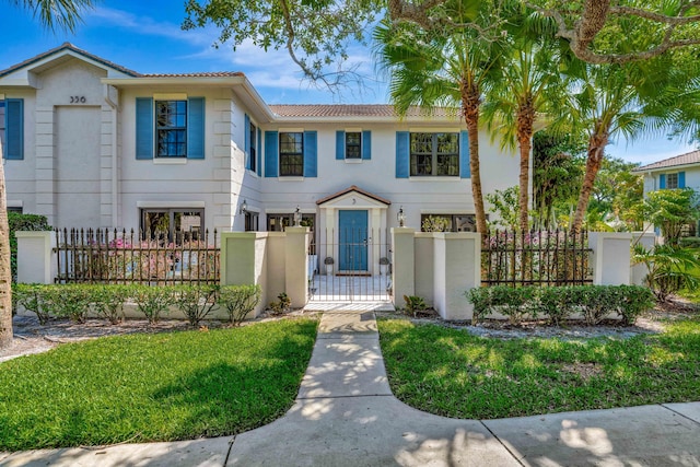 townhome / multi-family property with a gate, a tiled roof, stucco siding, and a fenced front yard