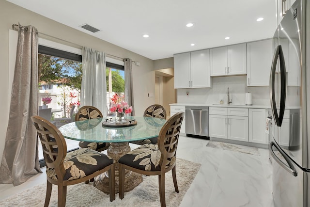 dining room with light marble finish floors, recessed lighting, and bar with sink