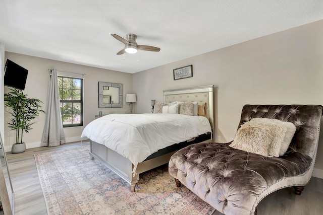 bedroom with light wood finished floors, a ceiling fan, and baseboards