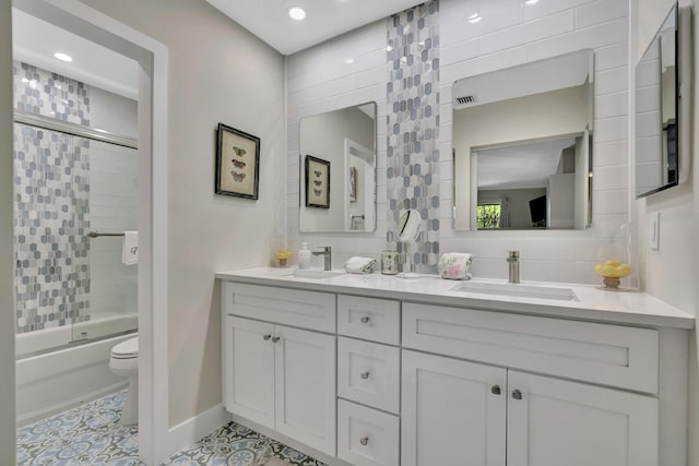 bathroom with toilet, double vanity, enclosed tub / shower combo, baseboards, and tile patterned flooring