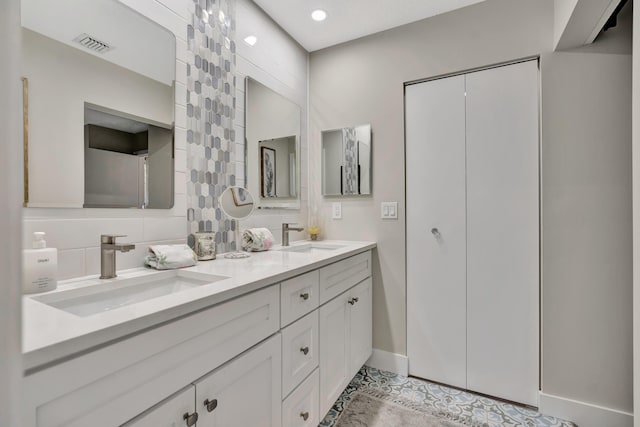 full bathroom with double vanity, baseboards, and backsplash