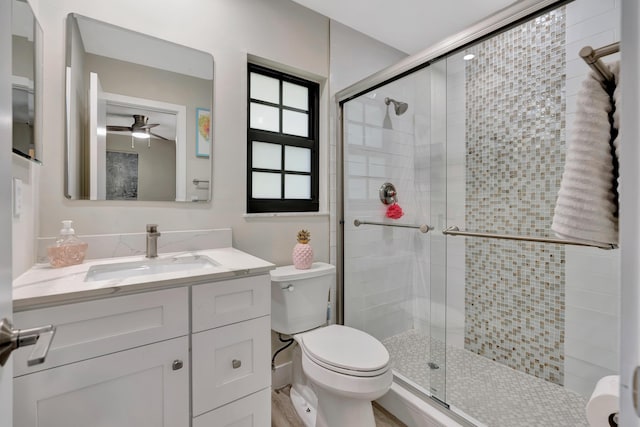 full bath featuring a shower stall, ceiling fan, toilet, and vanity