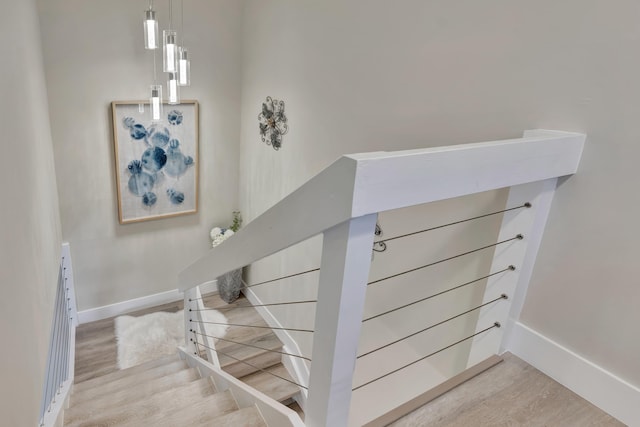 staircase featuring wood finished floors and baseboards