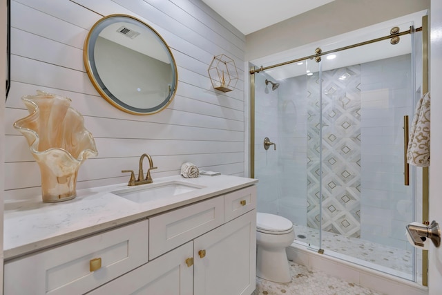 bathroom featuring a stall shower, toilet, vanity, and wooden walls