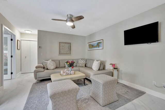living room featuring marble finish flooring, a ceiling fan, and baseboards
