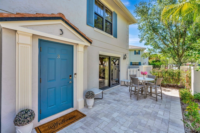 property entrance with stucco siding, outdoor dining space, and a patio