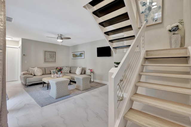 living area with stairs, ceiling fan, and marble finish floors