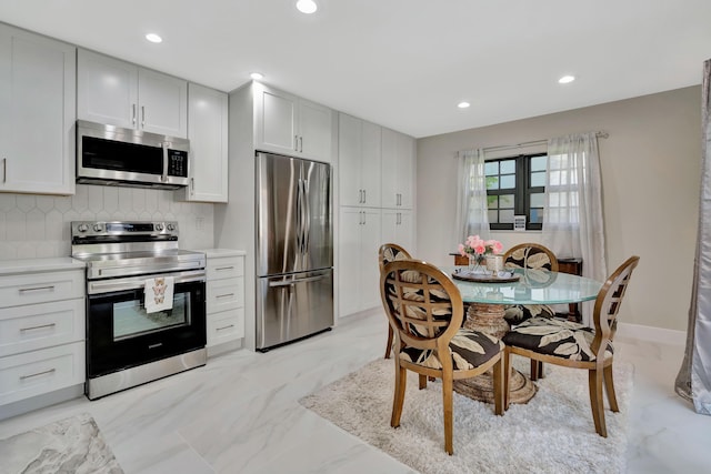 kitchen with stainless steel appliances, tasteful backsplash, light countertops, recessed lighting, and light marble finish floors