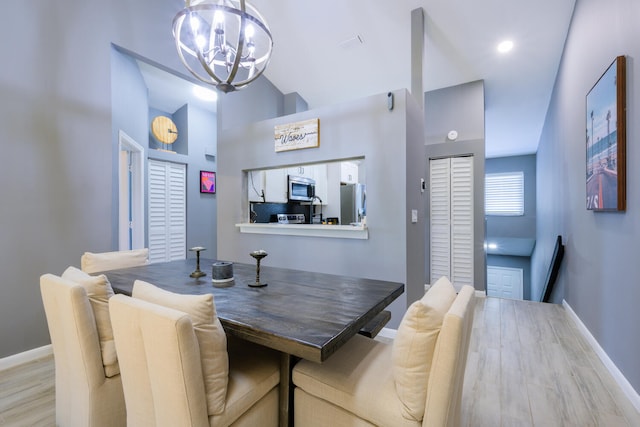 dining area featuring a chandelier, baseboards, and light wood finished floors